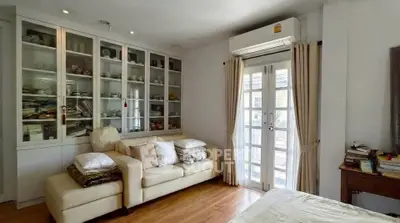 Charming living room with cozy sofa and elegant glass cabinet, featuring natural light from French doors.