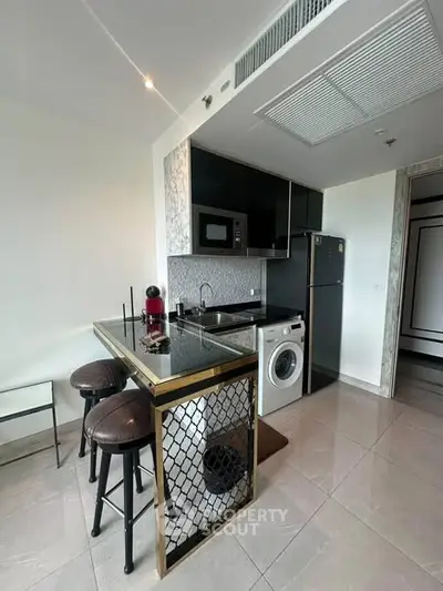 Modern kitchen with sleek black cabinets, built-in appliances, and stylish breakfast bar seating.