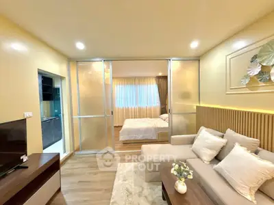Modern living room with cozy sofa and sliding doors leading to a bright bedroom, perfect for urban living.
