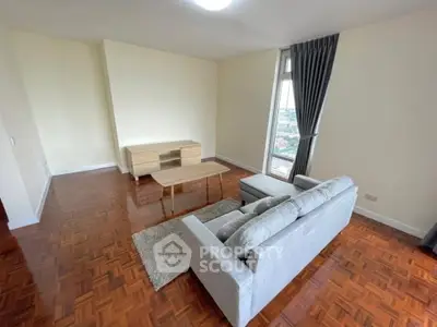 Spacious living room with modern furniture and large window offering city views.