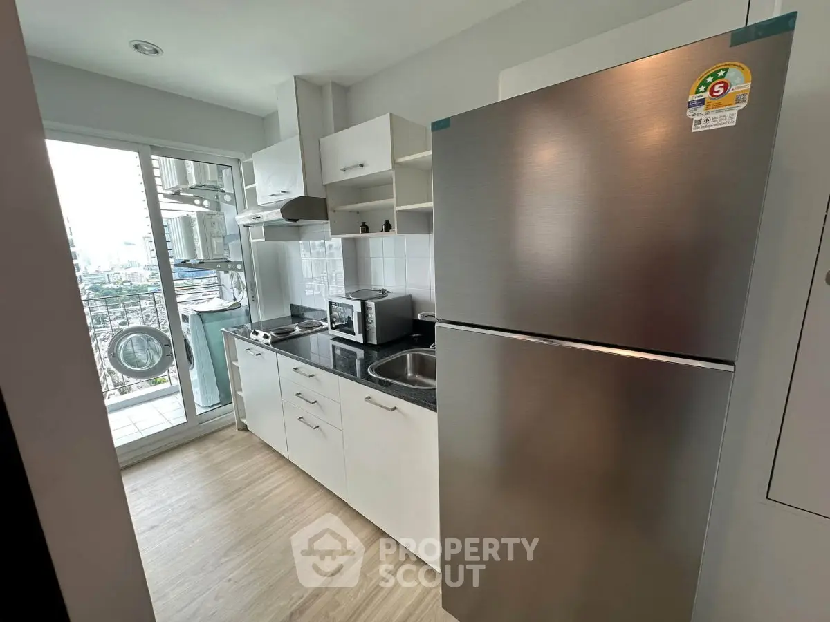 Modern kitchen with stainless steel appliances and balcony view in a stylish apartment.