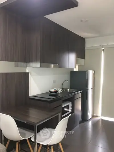 Modern kitchen with sleek cabinetry and compact dining area in a stylish apartment.