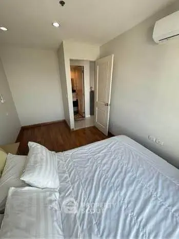 Cozy bedroom with wooden flooring and air conditioning, perfect for relaxation.
