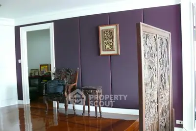 Elegant living room with polished wooden floors and ornate furniture, featuring a decorative wall panel and artwork.