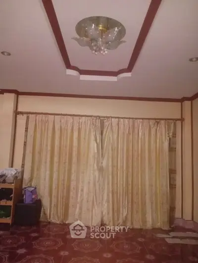 Spacious living room with elegant ceiling light and large window draped with luxurious curtains.