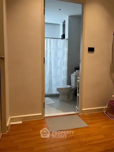 Modern bathroom with wooden flooring and shower curtain, ideal for urban living.
