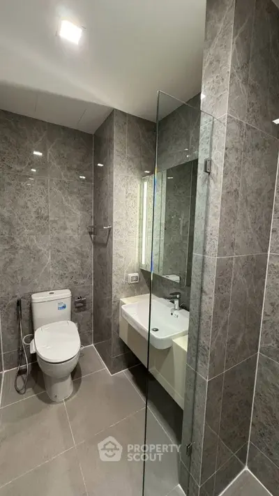 Modern bathroom with sleek gray tiles and glass shower enclosure