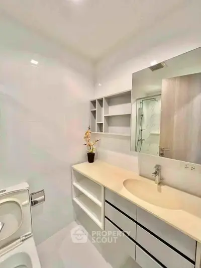 Modern bathroom with sleek design, featuring a spacious vanity and elegant fixtures.