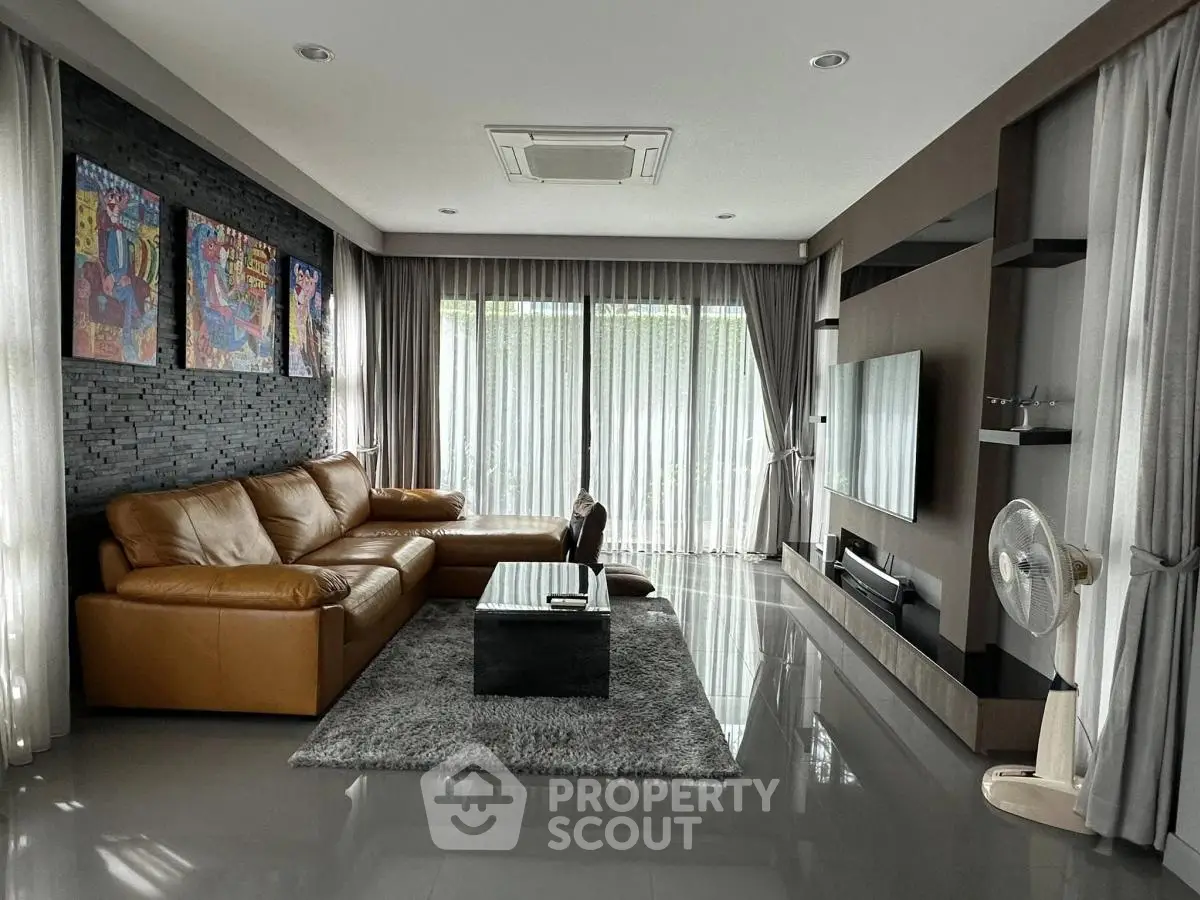 Spacious modern living room with leather sofa and large TV, perfect for relaxation.
