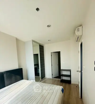 Modern bedroom with sleek design, featuring a comfortable bed, built-in wardrobe, and air conditioning.