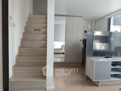 Modern interior with wooden staircase and sleek furniture in a compact living space.
