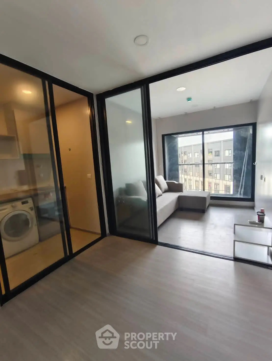 Modern apartment with glass partitions and city view, featuring a cozy living area and in-unit laundry.