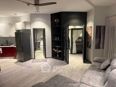 Modern open-plan living room with sleek kitchen and cozy bedroom access, perfect for stylish urban living.