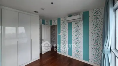 Charming bedroom with stylish wallpaper and air conditioning, featuring a spacious wardrobe and elegant wooden flooring.
