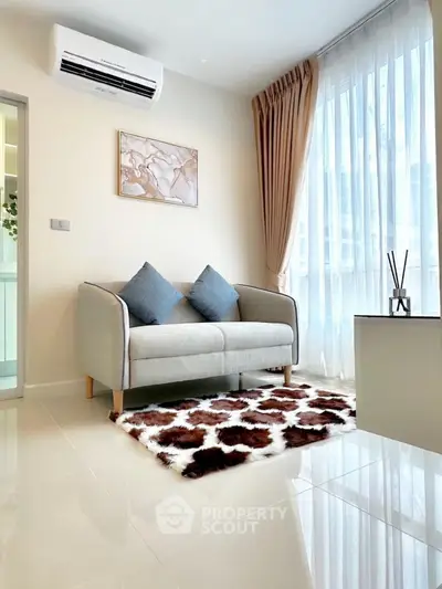 Modern living room with stylish sofa, air conditioning, and natural light from large windows.
