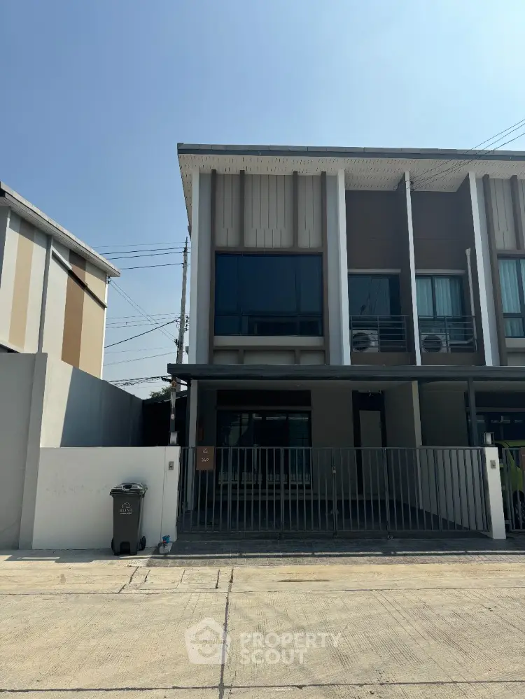 Modern townhouse exterior with sleek design and gated entrance in a sunny neighborhood.