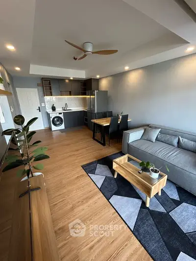 Modern living room with open kitchen, stylish furniture, and wooden flooring in a cozy apartment.