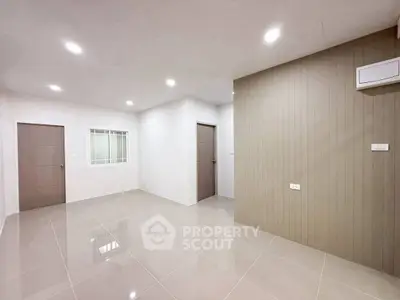 Spacious modern living room with sleek tile flooring and neutral walls, perfect for customization.