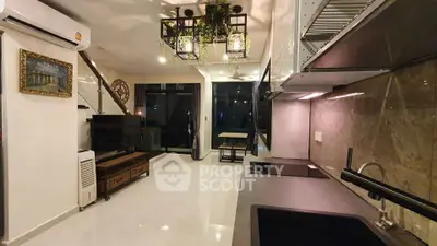 Modern open-layout kitchen with sleek appliances and stylish lighting in a contemporary apartment.