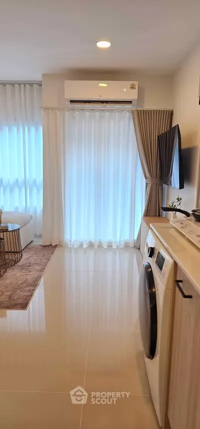 Modern living room with air conditioning and washing machine, featuring sleek design and natural light.