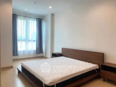 Spacious bedroom with modern wooden furniture and large window for natural light.