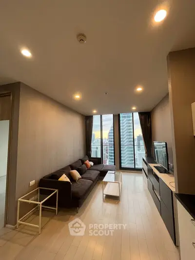 Modern living room with city view, featuring sleek furniture and large windows in a high-rise apartment.