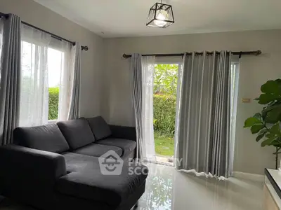 Cozy living room with modern gray sofa and large windows overlooking a lush garden.