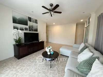 Spacious living room with modern decor and ceiling fan, featuring a cozy sectional sofa and elegant wall art.