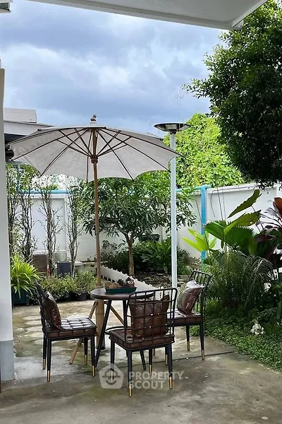 Charming garden patio with seating and umbrella, perfect for outdoor relaxation.