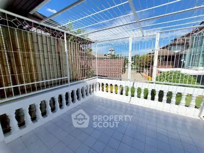 Spacious tiled balcony with white railing and clear blue sky view.