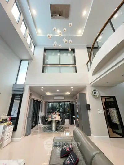 Luxurious modern living room with high ceilings and elegant chandelier in a spacious open-plan design.
