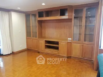 Spacious living room with elegant wooden built-in shelves and polished parquet flooring.