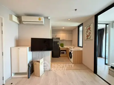 Modern open-plan living room with kitchen, featuring air conditioning and washing machine.