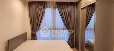 Cozy bedroom with elegant curtains and a large window, perfect for natural light lovers.