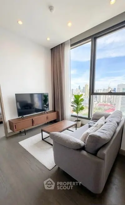 Modern living room with city view, featuring a cozy sofa, sleek TV stand, and large windows for natural light.