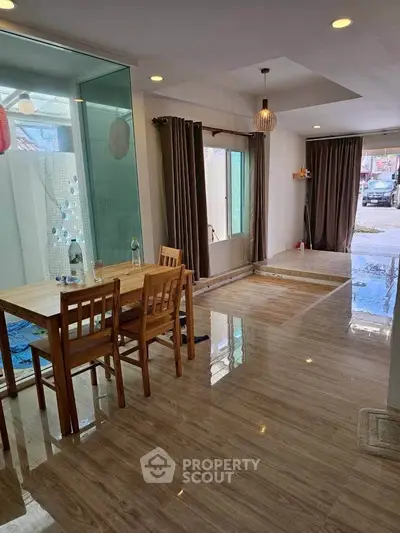 Spacious open-plan living area with dining set and large windows, perfect for natural light.