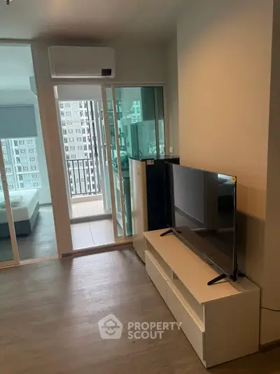 Modern apartment interior with TV, air conditioning, and balcony view.