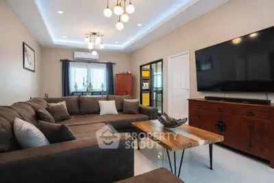 Spacious living room with modern decor and large TV, perfect for relaxation.
