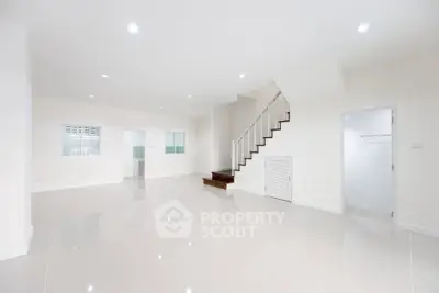 Spacious open-plan living area with staircase and glossy tiled floors in modern home.