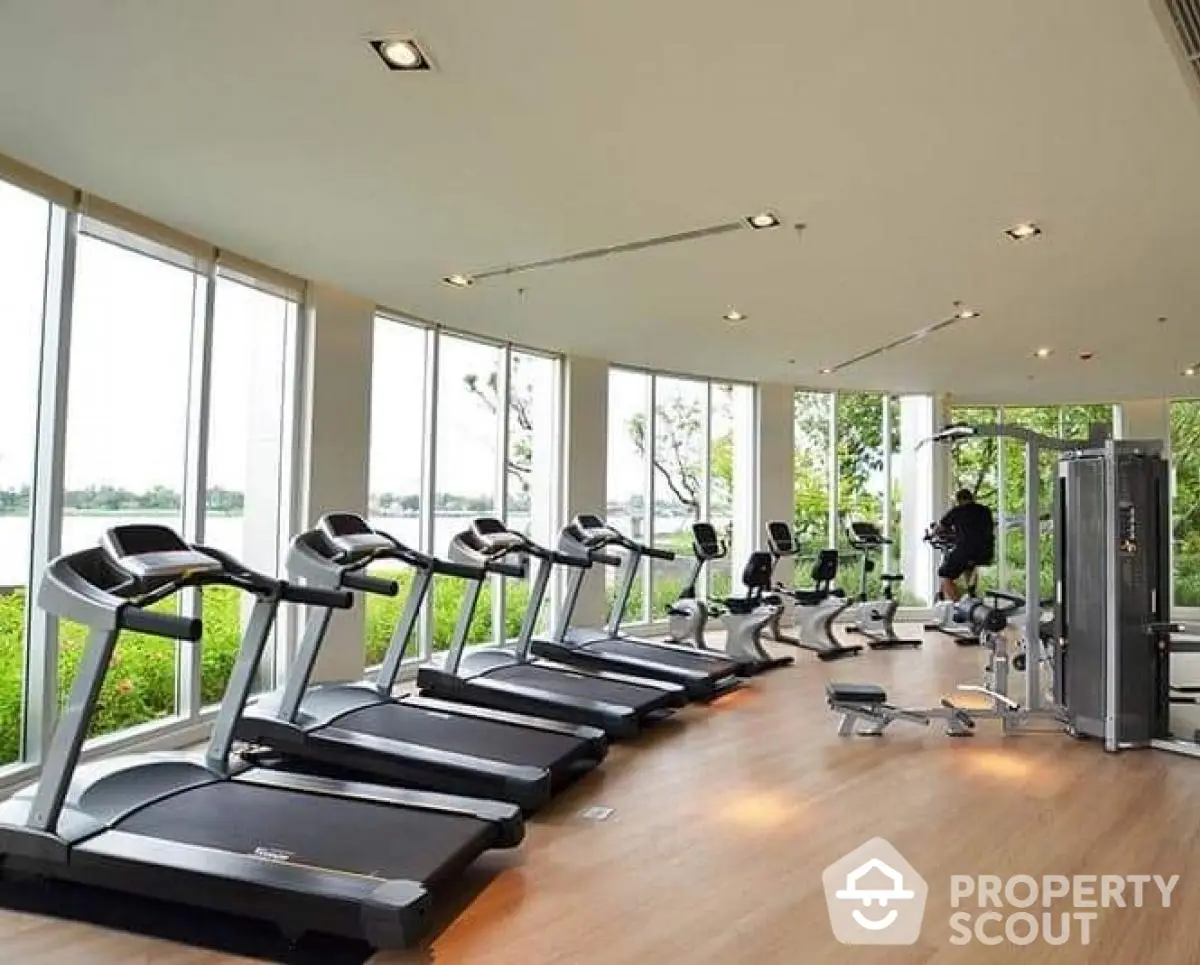 Spacious gym with modern equipment and scenic views in luxury residential complex.