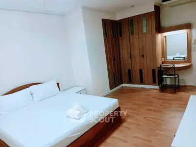 Spacious bedroom with wooden flooring and built-in wardrobe in modern apartment.