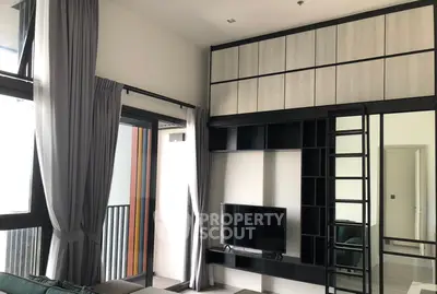 Modern living room with high ceiling, large windows, and stylish built-in shelving unit.