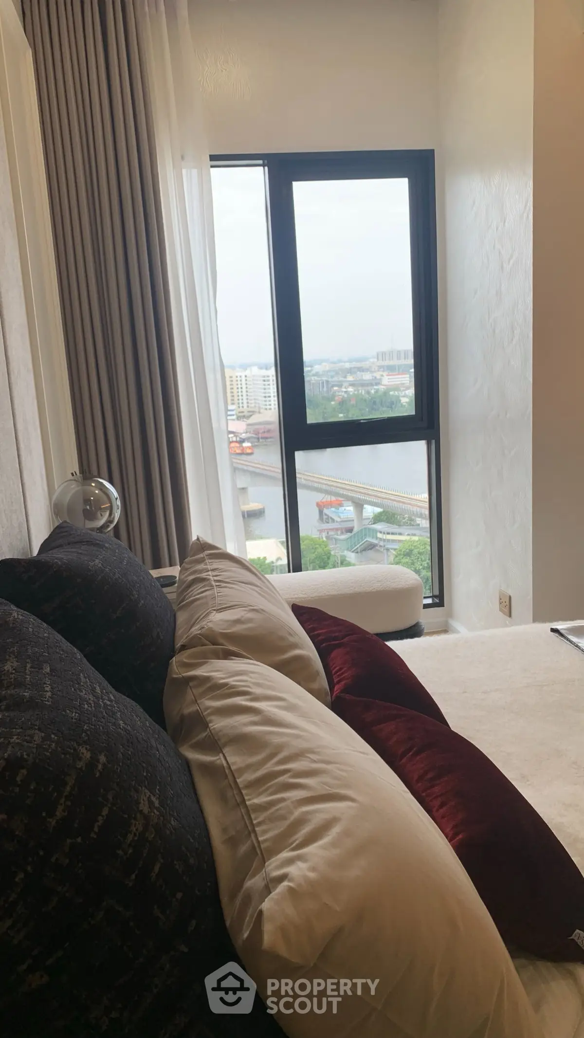 Luxurious living room with stunning river view through large window, plush cushions, and elegant decor.