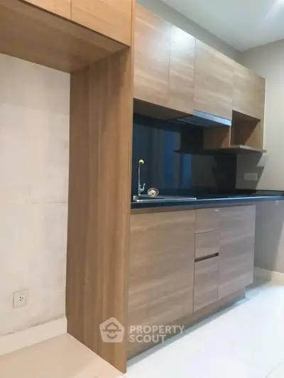 Modern kitchen with sleek wooden cabinets and black countertop in a contemporary apartment.