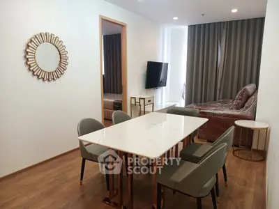 Modern dining area with elegant table and chairs, adjacent to a cozy living space with a TV and stylish decor.