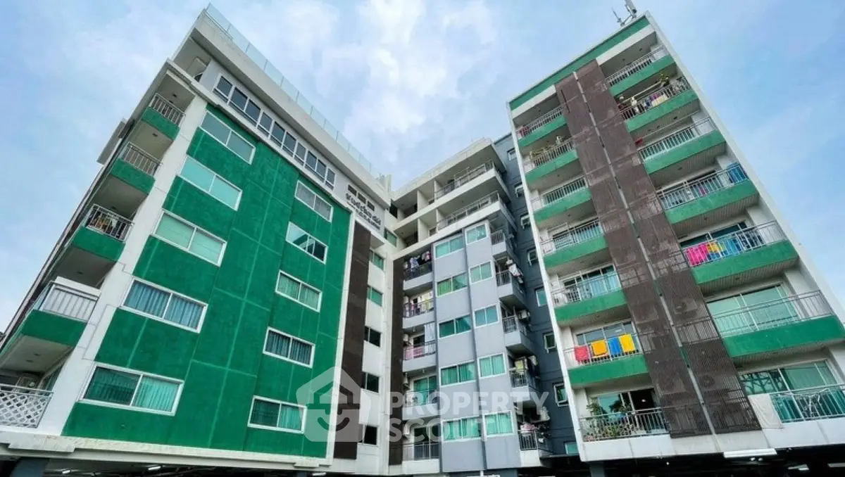 Modern multi-story apartment building with vibrant green facade and balconies.