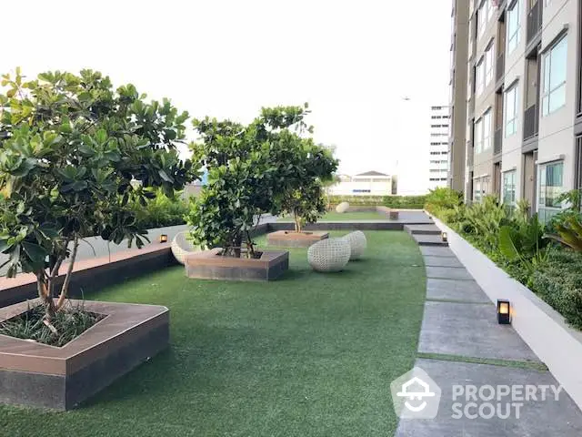 Modern apartment building with lush green garden and seating area