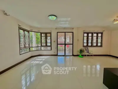 Spacious living room with large windows and glossy tiled floor, perfect for natural light lovers.