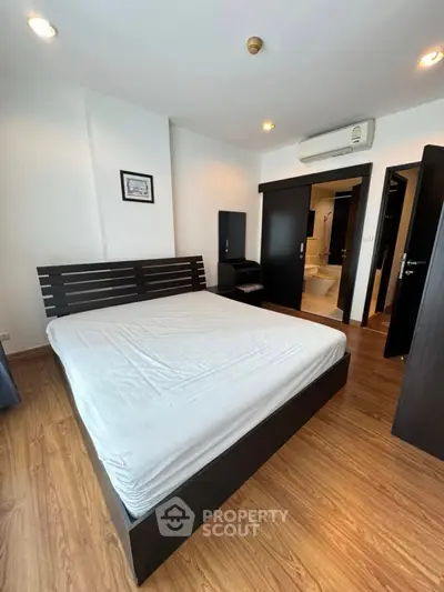 Spacious bedroom with modern furnishings and wooden flooring in a stylish apartment.