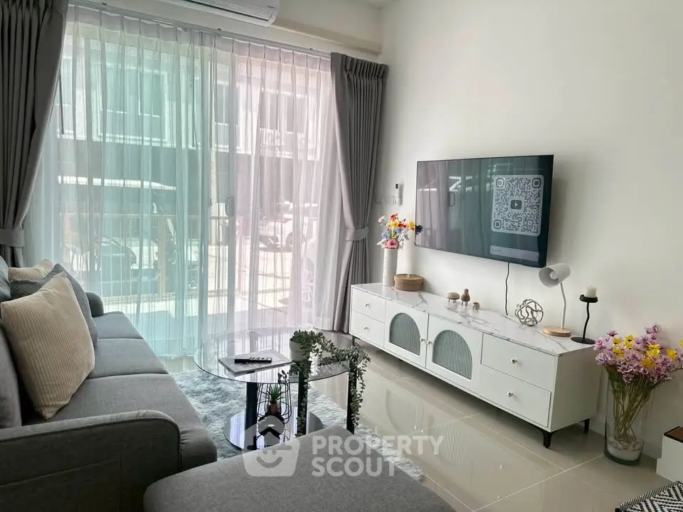 Modern living room with sleek furniture and large window, perfect for cozy gatherings.